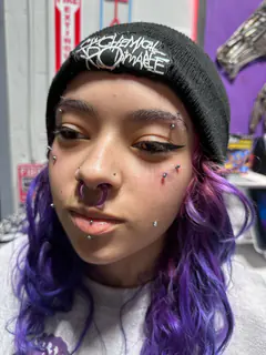 Multiple facial piercings with decorative jewelry completed by Mikey